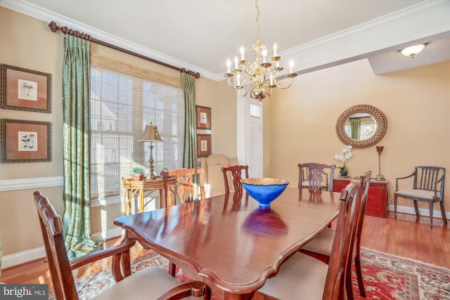 dining area with hardwood / wood-style flooring, ornamental molding, and an inviting chandelier