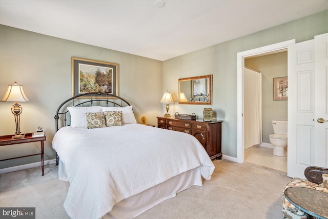 bedroom with connected bathroom and light carpet