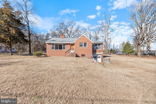 view of front of home featuring a chimney, a front lawn, and brick siding