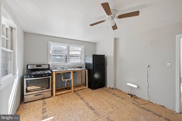 kitchen with freestanding refrigerator, a sink, and gas range