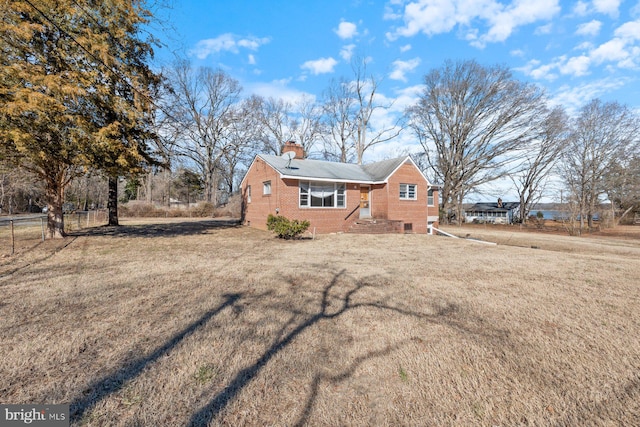 exterior space with brick siding, a lawn, and a chimney