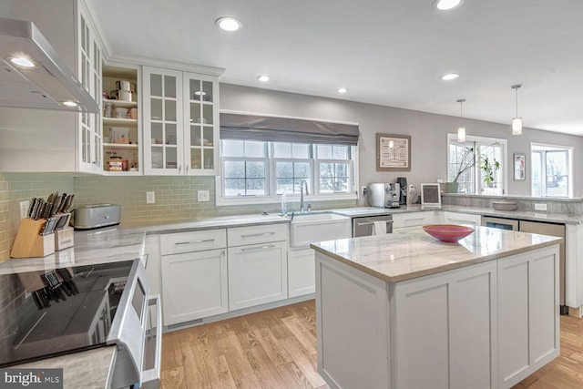 kitchen featuring white cabinetry, sink, decorative light fixtures, and range hood