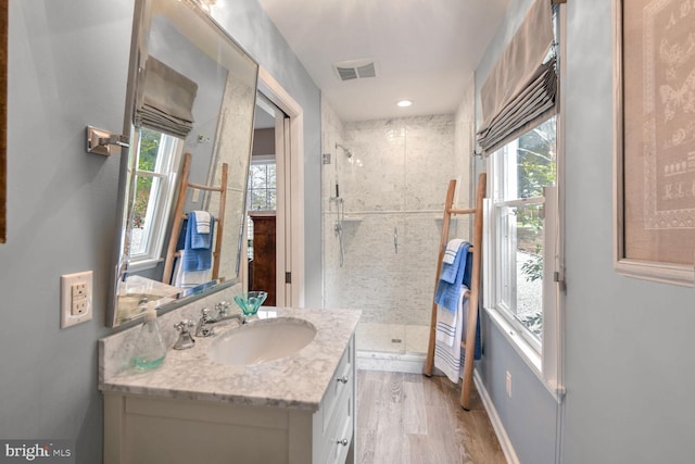 bathroom with walk in shower, vanity, and hardwood / wood-style floors