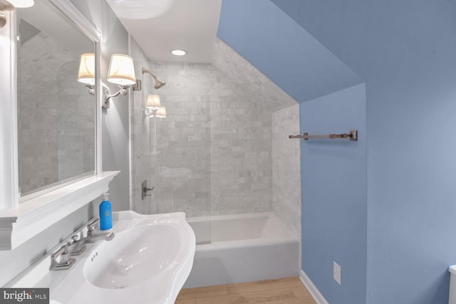 bathroom with tiled shower / bath combo, sink, and hardwood / wood-style floors