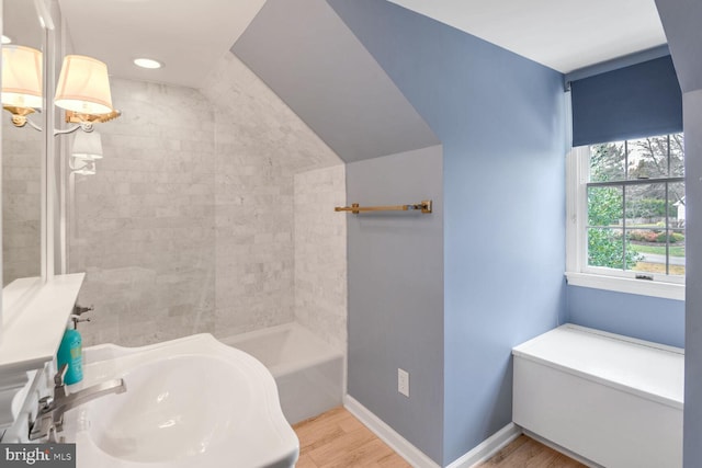 bathroom with wood-type flooring, tiled shower / bath combo, and sink