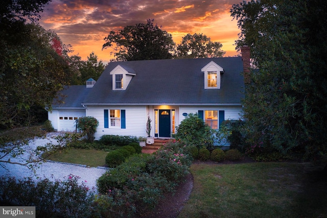 cape cod home featuring a garage and a yard