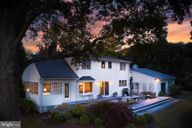 back house at dusk with a deck