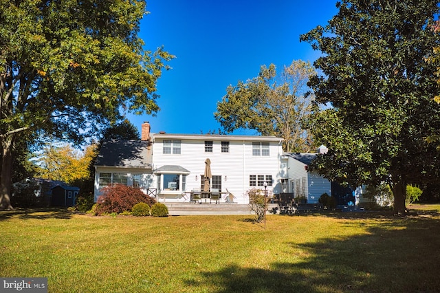 back of house featuring a storage unit, a deck, and a lawn