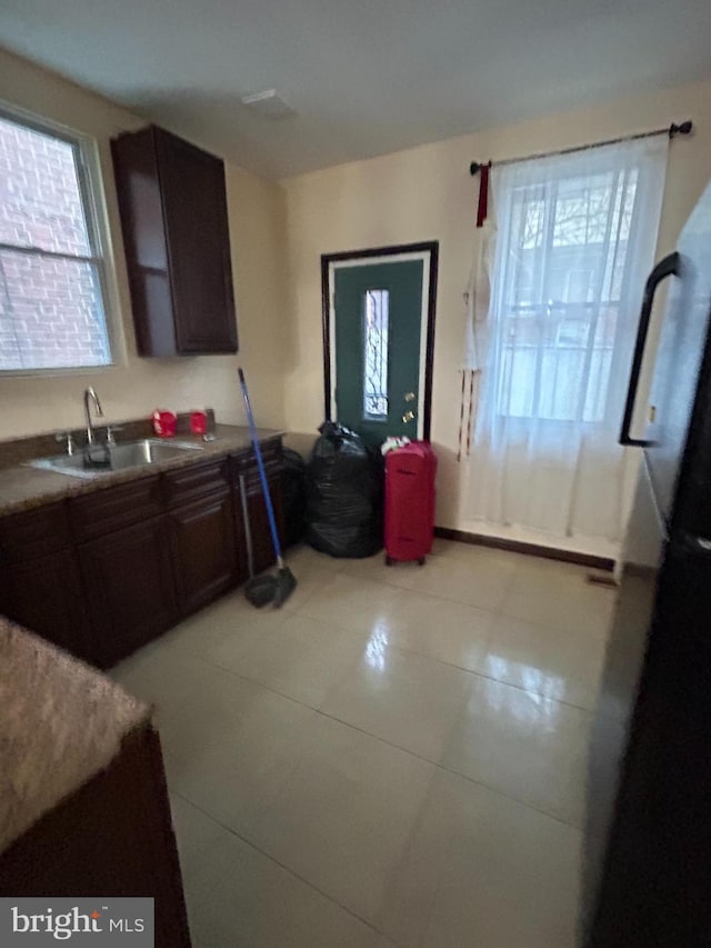 kitchen with tile patterned floors, dark brown cabinetry, and sink