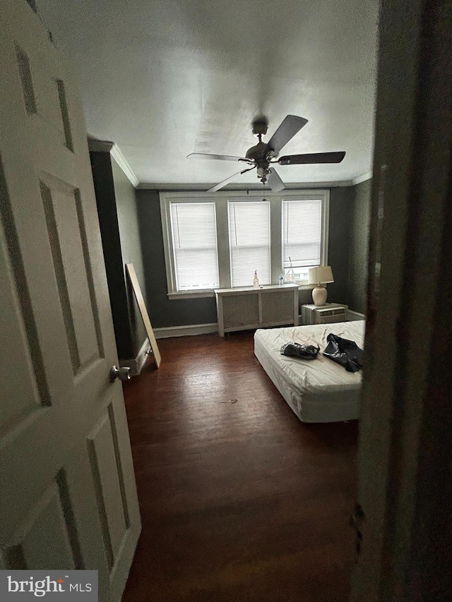 bedroom with ornamental molding, dark wood-type flooring, and ceiling fan