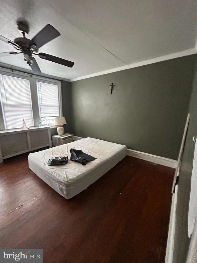 unfurnished bedroom featuring dark hardwood / wood-style flooring, ornamental molding, and ceiling fan