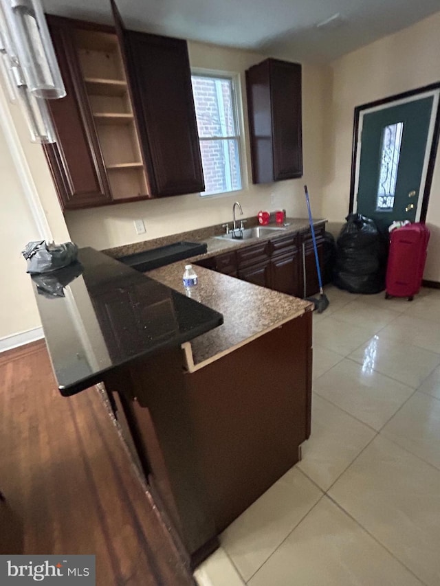 kitchen featuring a kitchen breakfast bar, sink, light tile patterned floors, and dark brown cabinetry