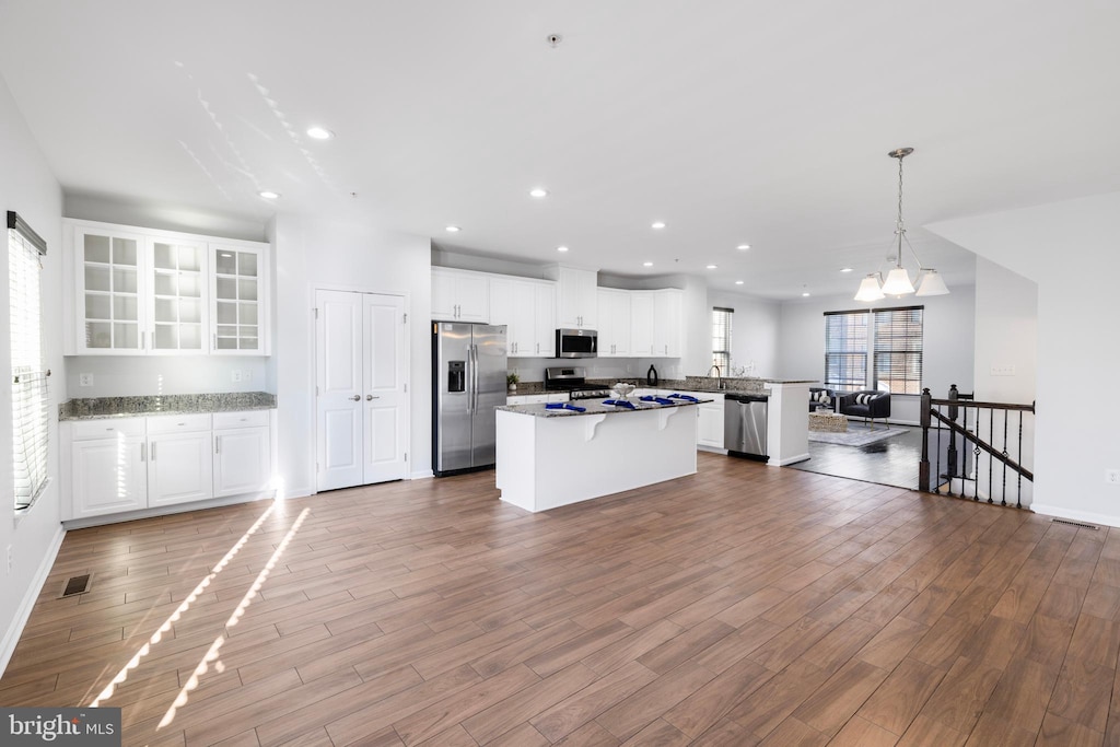 kitchen featuring white cabinetry, hanging light fixtures, a center island, and appliances with stainless steel finishes