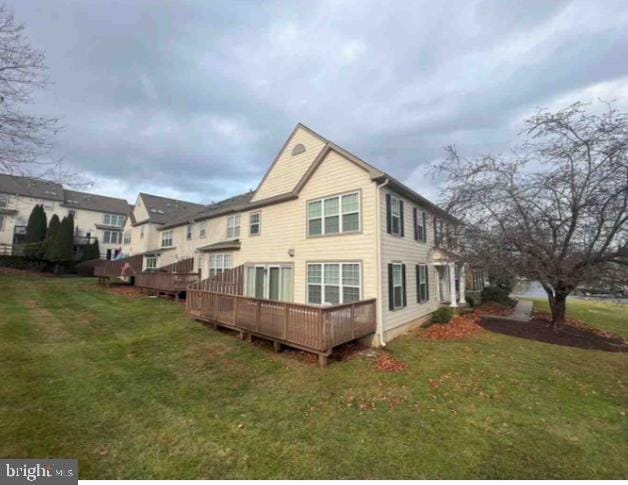 back of property featuring a wooden deck and a yard