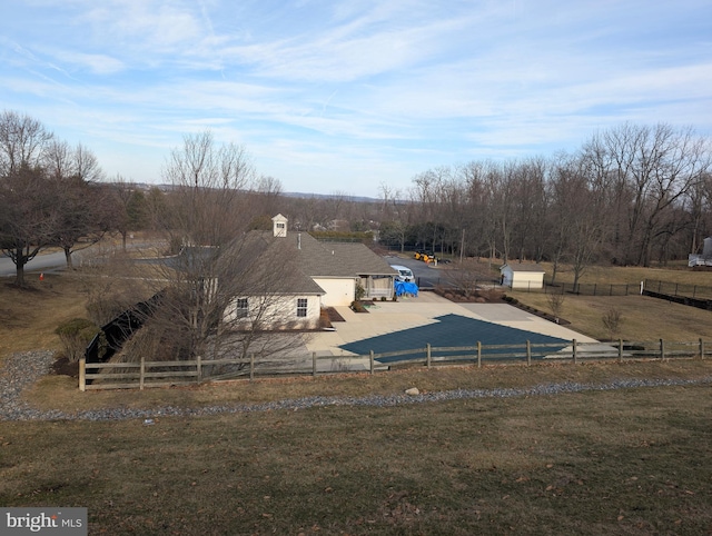 view of swimming pool featuring a yard, a rural view, and fence