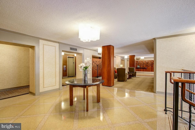 hallway with crown molding, baseboards, visible vents, and a textured ceiling