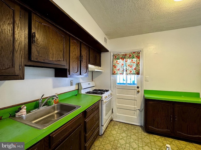 kitchen with dark brown cabinetry, white gas range, sink, and a textured ceiling