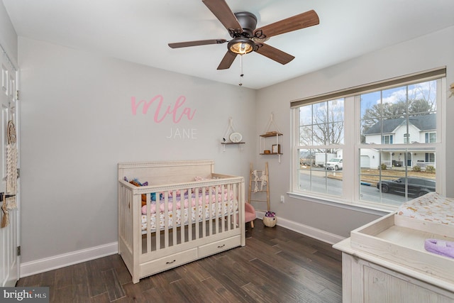 bedroom featuring a crib, dark hardwood / wood-style floors, and ceiling fan