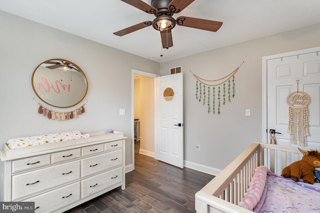 bedroom featuring dark wood-type flooring, ceiling fan, and a nursery area