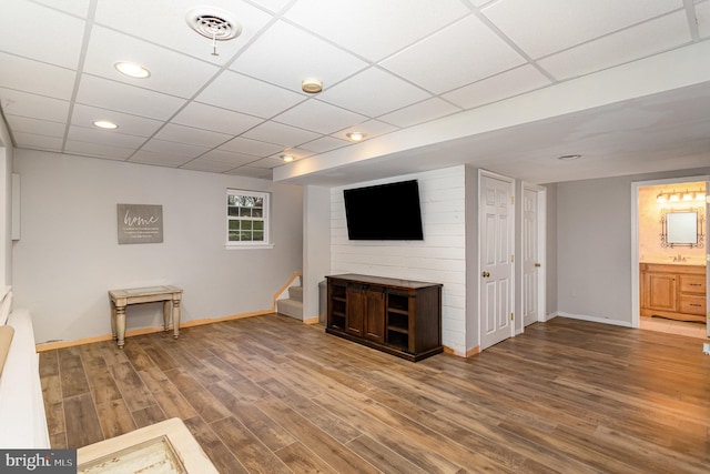 interior space with a drop ceiling and wood-type flooring