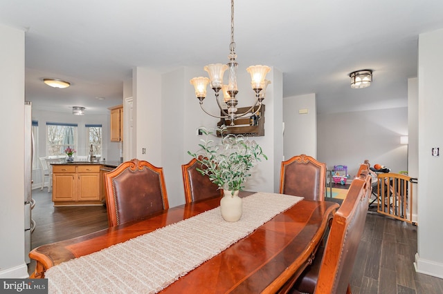 dining area featuring dark hardwood / wood-style flooring, a notable chandelier, and sink