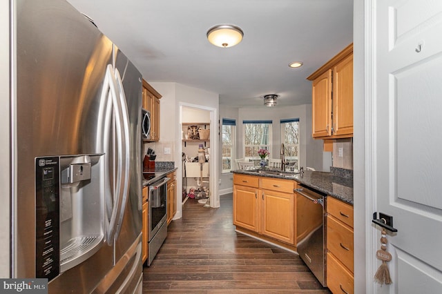 kitchen featuring dark stone countertops, sink, dark hardwood / wood-style flooring, and stainless steel appliances