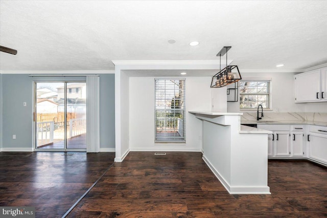 kitchen with white cabinetry, sink, decorative light fixtures, and a healthy amount of sunlight