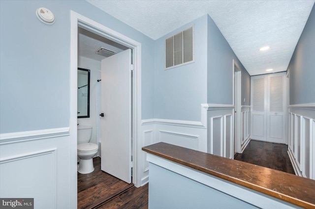 interior space with wood-type flooring, toilet, and a textured ceiling