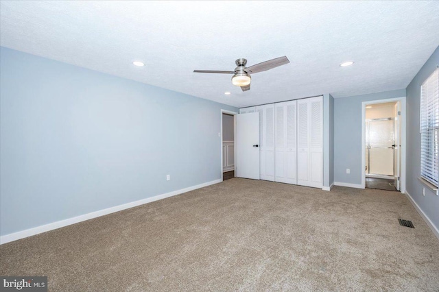 unfurnished bedroom featuring ceiling fan, connected bathroom, carpet, and a textured ceiling