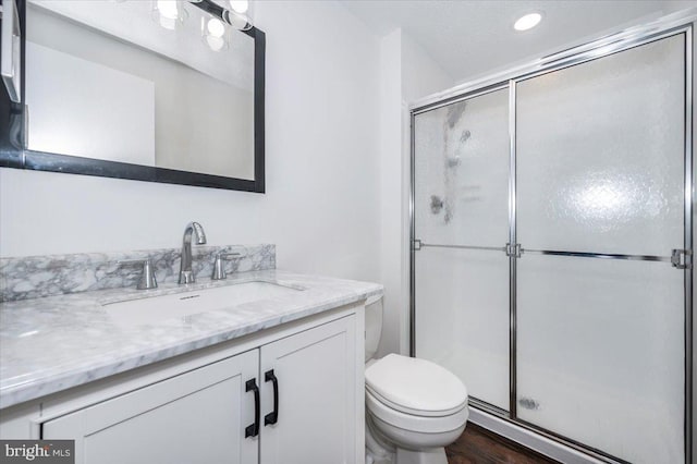 bathroom featuring vanity, toilet, a shower with door, and hardwood / wood-style floors