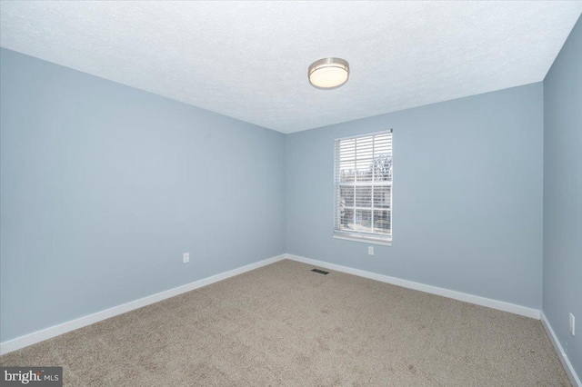 carpeted empty room with a textured ceiling