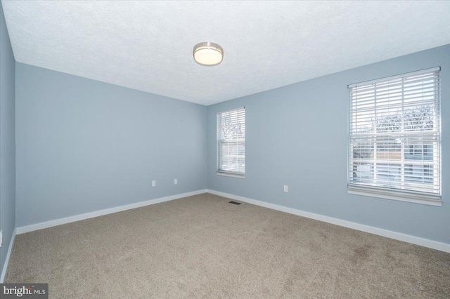 carpeted empty room featuring a textured ceiling