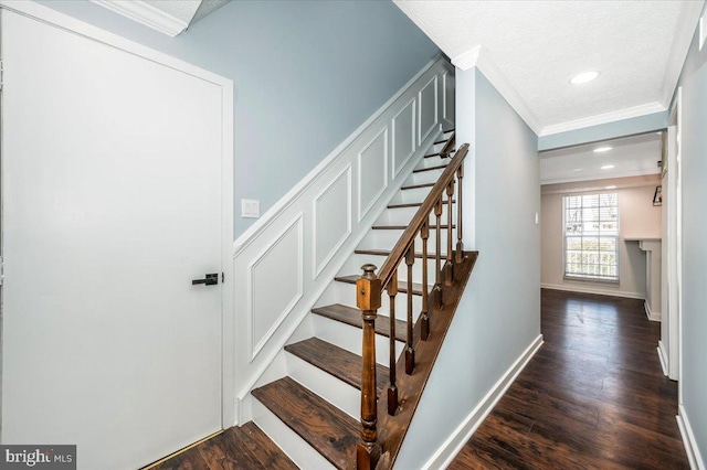 staircase featuring hardwood / wood-style floors, crown molding, and a textured ceiling