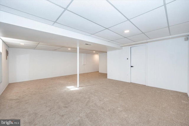 basement featuring a paneled ceiling and carpet flooring