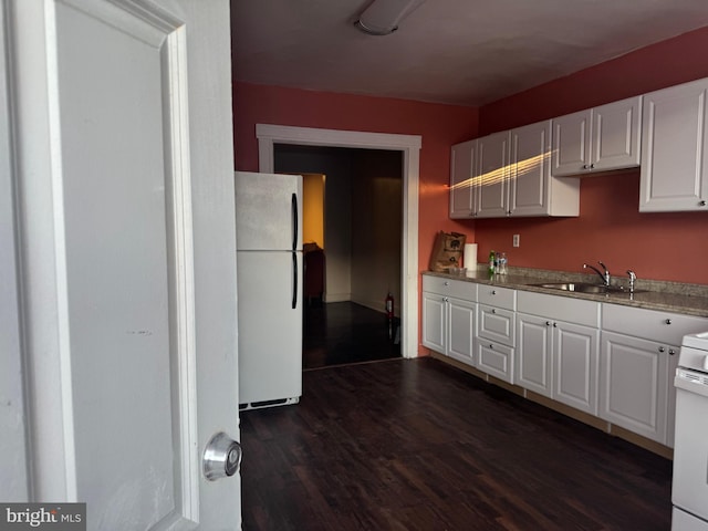 kitchen with white cabinetry, white appliances, dark hardwood / wood-style flooring, and sink