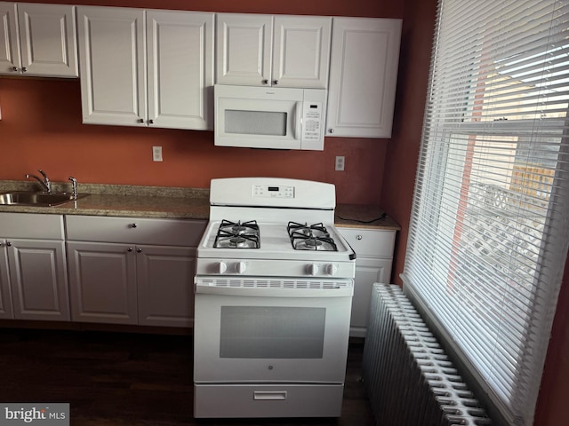 kitchen with radiator, sink, white cabinets, dark hardwood / wood-style flooring, and white appliances