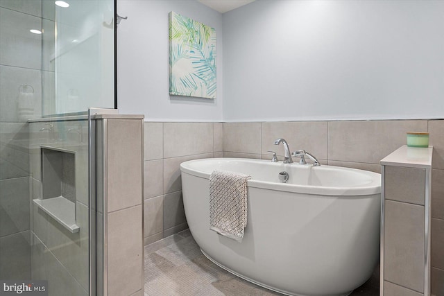 bathroom with tile patterned floors, shower with separate bathtub, and tile walls