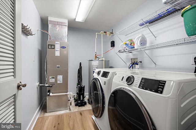 laundry area featuring separate washer and dryer, heating unit, and light wood-type flooring