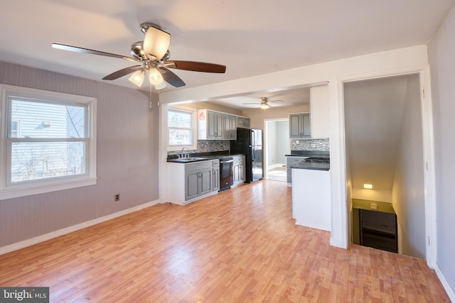 kitchen with sink, gray cabinetry, black refrigerator, decorative backsplash, and stainless steel dishwasher