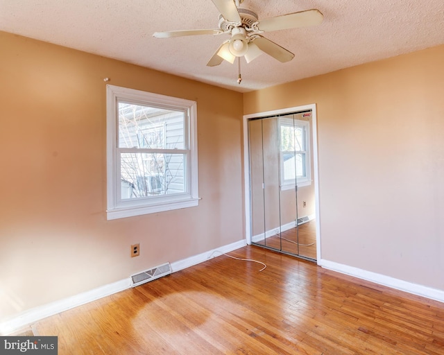 unfurnished bedroom featuring hardwood / wood-style flooring, a textured ceiling, and a closet