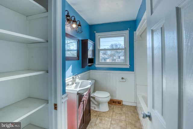 bathroom featuring vanity, a washtub, tile patterned floors, and toilet