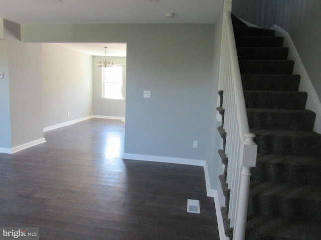 stairway with hardwood / wood-style floors and a notable chandelier