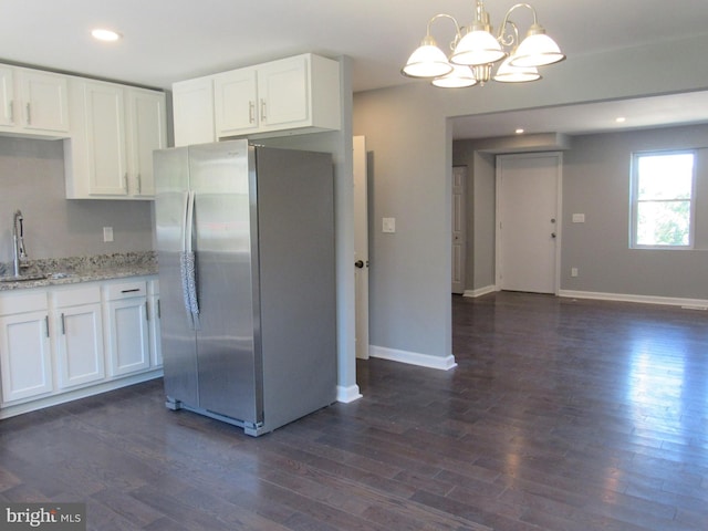 kitchen with dark wood-type flooring, stainless steel fridge, hanging light fixtures, and white cabinets