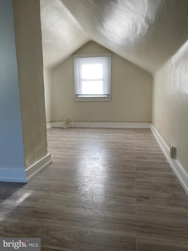 additional living space featuring lofted ceiling and dark hardwood / wood-style floors