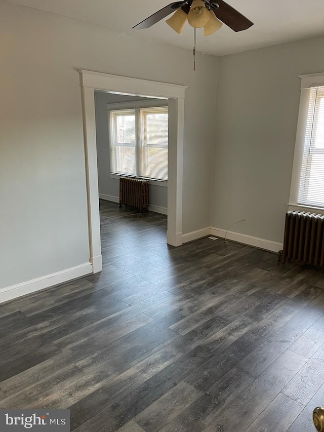 unfurnished room featuring radiator heating unit, dark hardwood / wood-style floors, and a wealth of natural light