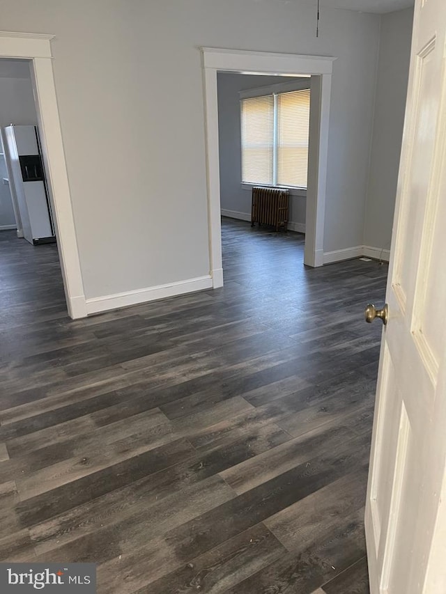 empty room with dark hardwood / wood-style floors and radiator heating unit