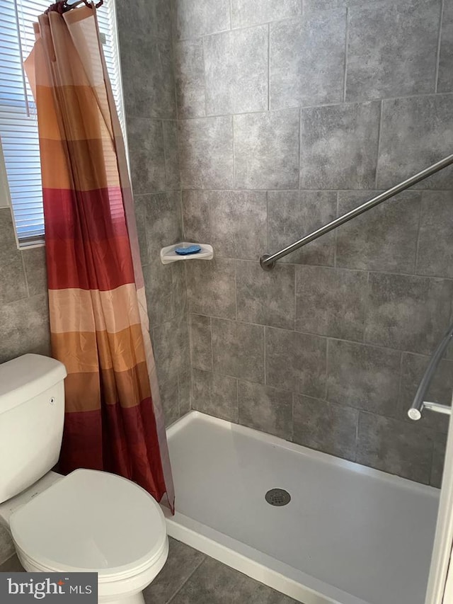 bathroom with a shower with curtain, a healthy amount of sunlight, tile patterned floors, and toilet