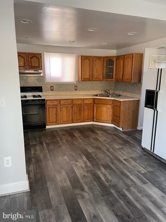 kitchen featuring gas range, white fridge with ice dispenser, dark wood-type flooring, and backsplash