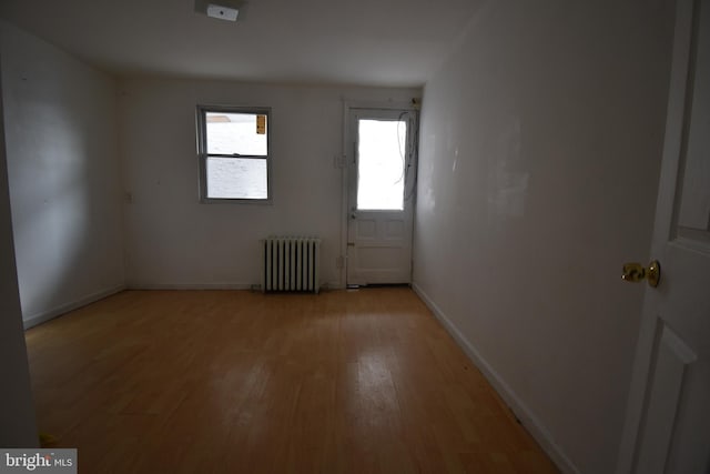 empty room featuring radiator and light hardwood / wood-style flooring