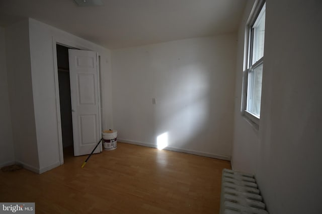 unfurnished bedroom featuring radiator heating unit and light hardwood / wood-style floors